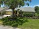 Home's exterior features beautiful landscaping, stone accents, and a mature shade tree at 4733 Spring Meadow Ln, Sarasota, FL 34233