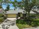 Home's exterior showcasing stone accents, two car garage, mature trees, and lush lawn at 4733 Spring Meadow Ln, Sarasota, FL 34233