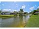 Tranquil pond view with lush green landscape and nearby homes in the distance at 4733 Spring Meadow Ln, Sarasota, FL 34233