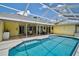 Aerial view of pool and patio with yellow house exterior and outdoor living area at 4733 Spring Meadow Ln, Sarasota, FL 34233