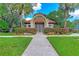 View of the Turtle Rock clubhouse entrance featuring a stone accented arched entry and lush landscaping at 4957 Sabal Lake Cir, Sarasota, FL 34238