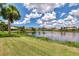 Expansive lake view with lush greenery, clear blue sky filled with fluffy white clouds, and manicured lawns at 4957 Sabal Lake Cir, Sarasota, FL 34238