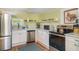 Well-lit kitchen with stainless steel appliances, white cabinets, and open shelving for storage at 509 Pine Ave # A, Anna Maria, FL 34216