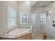 Bright bathroom featuring a soaking tub and shower with marble tile surround and glass door at 520 Rye Ne Rd, Bradenton, FL 34212