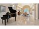 Elegant dining area with a black piano, arched entryway, and a formal dining set under a decorative chandelier at 520 Rye Ne Rd, Bradenton, FL 34212