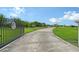 Long driveway with a gated entrance, manicured lawn, and lush landscaping at 520 Rye Ne Rd, Bradenton, FL 34212