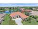 Stunning home with red tile roof, surrounded by lush greenery, manicured lawn, and a serene lake view at 5523 Secluded Oaks Way, Sarasota, FL 34233
