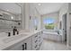 A gorgeous bathroom featuring a soaking tub beneath a picture window and & sinks at 5523 Secluded Oaks Way, Sarasota, FL 34233