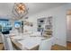 Modern dining room with a large white table, white chairs, and sleek geometric lighting at 5600 Beach Way Dr # 315, Sarasota, FL 34242