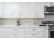 Close-up view of modern white kitchen cabinets and counters with stainless appliances and gold hardware at 5600 Beach Way Dr # 315, Sarasota, FL 34242