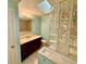 Bright bathroom featuring a glass block shower, vanity with solid surface countertop, tile flooring, and a skylight at 5615 Waneta Pl, Sarasota, FL 34231
