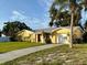 A single-story home with a well-kept lawn, a paved driveway, a red front door, and a white garage door at 5615 Waneta Pl, Sarasota, FL 34231