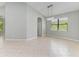 Bright dining room with beige tiling, light-grey walls, an arched doorway, and a modern chandelier fixture above a window at 6423 Royal Tern Cir, Lakewood Ranch, FL 34202