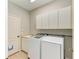 Laundry room featuring a washer, dryer, utility sink, cabinets, and tile floor, providing a functional space at 6423 Royal Tern Cir, Lakewood Ranch, FL 34202