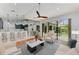 Open concept living room featuring hardwood floors, modern ceiling fan, neutral tones, and sliding glass doors to the screened patio at 6423 Royal Tern Cir, Lakewood Ranch, FL 34202
