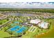 A high aerial view showcasing a community clubhouse, pool, tennis courts, and lake views at 6507 Clairborne Ln, Bradenton, FL 34211