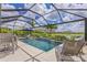 This screened-in pool features sun loungers, a seating area, and a beautiful waterfall feature with tropical landscaping at 6507 Clairborne Ln, Bradenton, FL 34211