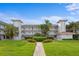 Exterior view of a three-story condo building with white balconies, beautiful landscaping, and a walkway at 6507 Stone River Rd # 304, Bradenton, FL 34203