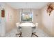 Cozy eat-in kitchen featuring a white table and chairs, window with blinds, and light striped walls at 6507 Stone River Rd # 304, Bradenton, FL 34203