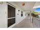 Condo hallway with white walls, screened-in doors, and tiled floors, featuring palm trees in the background at 6507 Stone River Rd # 304, Bradenton, FL 34203