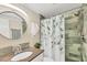 Well-appointed bathroom with granite countertop, round mirror, and a shower with leafy curtain at 6832 Woodwind Dr # 53, Sarasota, FL 34231
