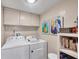 Bright laundry room features white washer and dryer, storage cabinets, colorful wall art, and convenient shelving at 6832 Woodwind Dr # 53, Sarasota, FL 34231