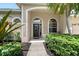 Inviting front porch with decorative glass front door, arched windows, and lush greenery at 7464 Ridge Rd, Sarasota, FL 34238