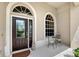 Inviting front porch with decorative glass front door, arched windows, and table set for two at 7464 Ridge Rd, Sarasota, FL 34238
