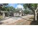 View of the driveway leading to a house with wood siding and a covered parking area behind a gated fence at 809 30Th E Ave, Bradenton, FL 34208