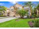 A lovely two-story home boasts lush landscaping and mature palm trees on a sunny day at 8168 Villa Grande Ct, Sarasota, FL 34243