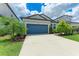 Charming single Gathering home showcasing a blue garage door and well-manicured landscaping at 8721 Firefly Pl, Parrish, FL 34219