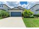 Charming single Gathering home showcasing a blue garage door and well-manicured landscaping at 8721 Firefly Pl, Parrish, FL 34219