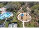 Aerial view of water park with a pool, playground, slides and swings amidst lush greenery and palm trees at 8721 Firefly Pl, Parrish, FL 34219
