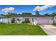 Charming single-story home with a well-manicured lawn, pink garage door, and tasteful landscaping at 912 Ponderosa Pine Ln, Sarasota, FL 34243