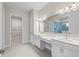 Bright bathroom featuring dual sinks, white cabinets, large mirror, and a door to the walk-in closet at 10309 Longmeadow Ave, Parrish, FL 34219