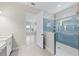 Modern bathroom showcasing a glass-enclosed shower, blue tile, and a white vanity with quartz countertop at 10309 Longmeadow Ave, Parrish, FL 34219