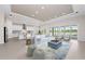 Open-concept living space with a modern kitchen, comfortable seating, and sliding glass doors opening to the pool area at 10309 Longmeadow Ave, Parrish, FL 34219