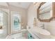 Bright bathroom with white shiplap wall, decorative mirror, and door leading to private pool area at 11915 Oak Ridge Dr, Parrish, FL 34219