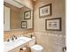 Elegant powder room featuring neutral textured wallpaper, decorative art, and a beautifully framed mirror at 12448 Highfield Cir, Lakewood Ranch, FL 34202