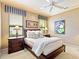 A bedroom features a queen bed, neutral carpeting, and elegant striped window treatments at 12448 Highfield Cir, Lakewood Ranch, FL 34202