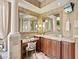 A vanity area in the main bathroom features mirrors, wood cabinetry, granite countertops, and a makeup vanity at 12448 Highfield Cir, Lakewood Ranch, FL 34202