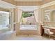 A luxurious main bathroom featuring a tub with tile surround and columns, plus a vanity area at 12448 Highfield Cir, Lakewood Ranch, FL 34202