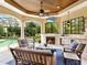 Covered outdoor patio with fireplace and plenty of seating, adjacent to a large screened in pool area at 12448 Highfield Cir, Lakewood Ranch, FL 34202