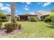 Home's backyard featuring a well-maintained lawn, vibrant plants, and a cozy screened lanai at 13805 Posada St, Venice, FL 34293