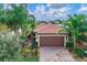 Charming home featuring a tile roof, lush landscaping, and a two-car garage at 13805 Posada St, Venice, FL 34293
