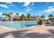 Beautiful outdoor pool with surrounding lounge area, palm trees and community clubhouse at 13805 Posada St, Venice, FL 34293