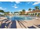 Beautiful outdoor pool with surrounding lounge area, palm trees and community clubhouse at 13805 Posada St, Venice, FL 34293