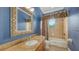 A blue bathroom features a marble countertop and bathtub, enhanced by natural light from a window at 1512 3Rd Street E Cir, Palmetto, FL 34221