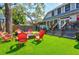 Backyard view from deck with artificial turf, fire pit with Adirondack chairs, and lush landscaping at 1523 1St W Ave, Bradenton, FL 34205
