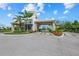 Community entrance featuring a stone gatehouse, palm trees, and vibrant landscaping at 15813 San Lazzaro Ave, Bradenton, FL 34211
